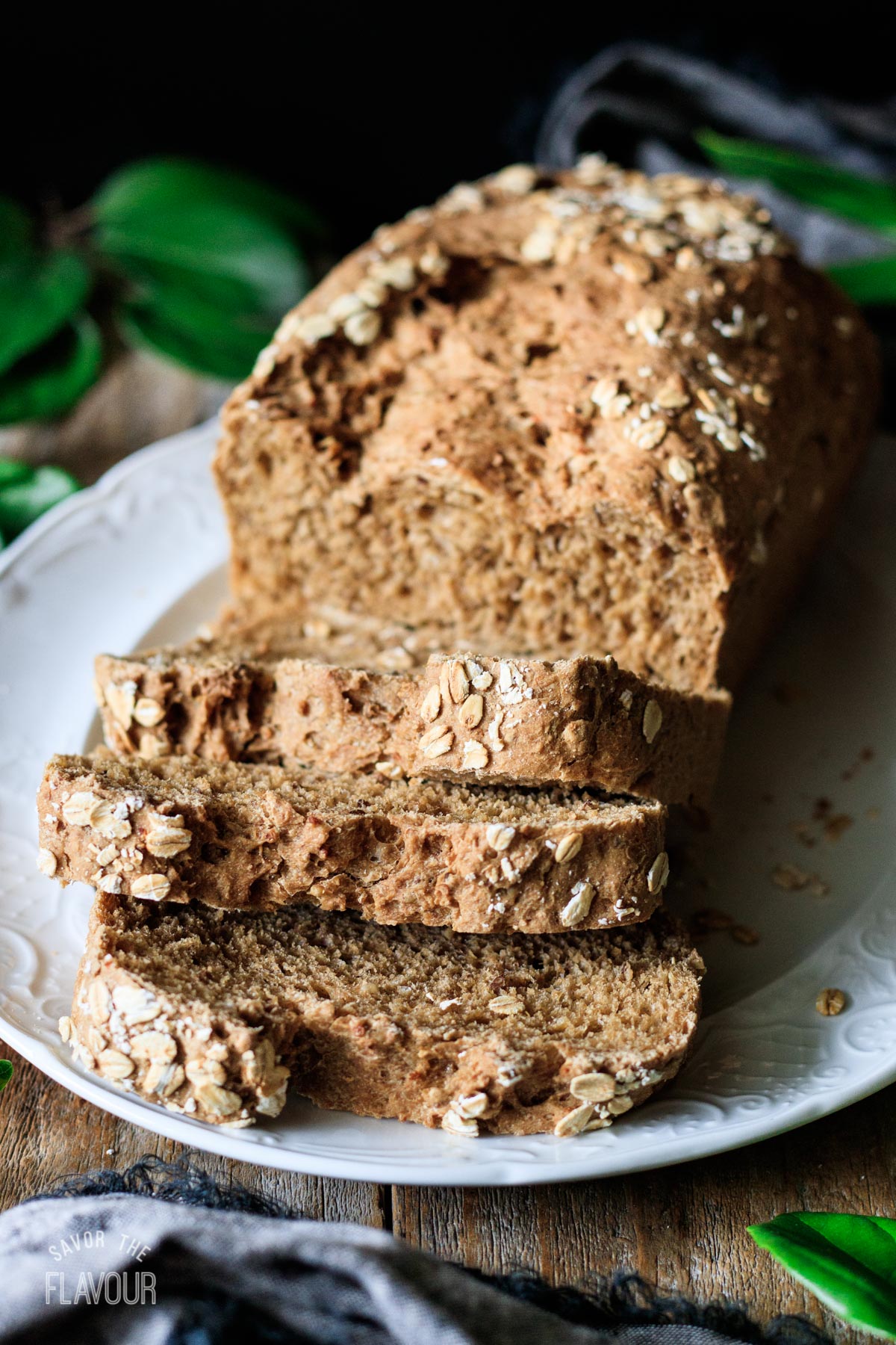 slices of multigrain bread on a white platter with the loaf