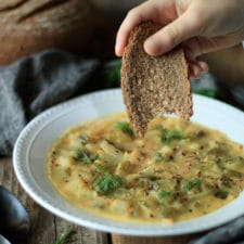 person dipping rye bread into dill pickle soup