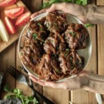 person holding a white plate of Salisbury steak with onion gravy