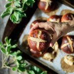person holding a German pretzel bun with greenery and a cookie sheet