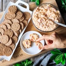 person holding a cracker spread with pimento cheese
