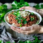 person holding a white bowl of red beans and rice