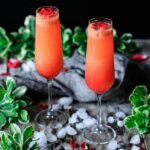 two strawberry citrus blush drinks with greenery, crushed ice, and rose petals