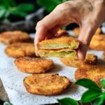 person holding a fried green tomato cut in half