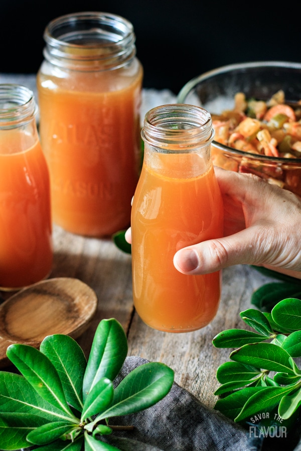 holding a glass bottle of seafood stock