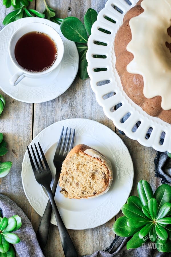 slice of maple walnut bundt cake on a plate with a cup of tea