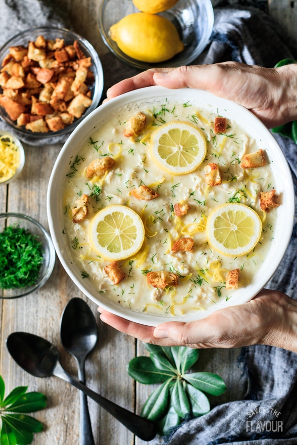 holding a bowl of Greek lemon chicken soup