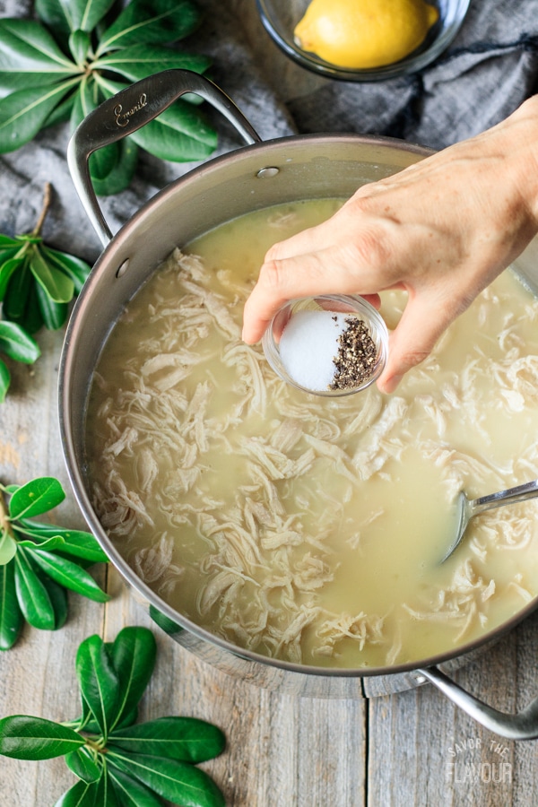adding salt and pepper to Greek lemon chicken soup