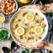 holding a bowl of Greek lemon chicken soup