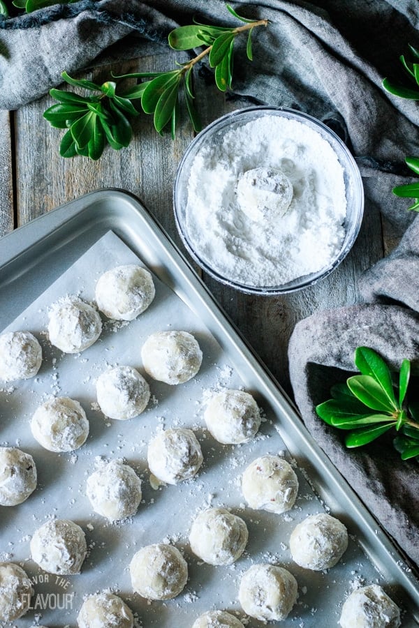 rolling Mexican wedding cookies in powdered sugar