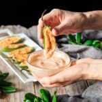 dipping one of the jalapeño poppers into sriracha mayo