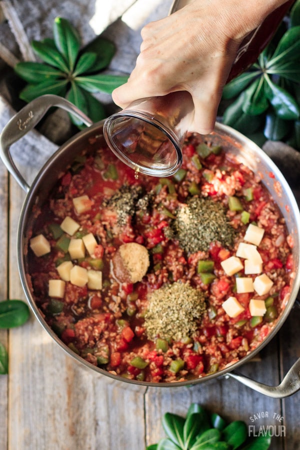 pouring beef stock into stuffed pepper soup