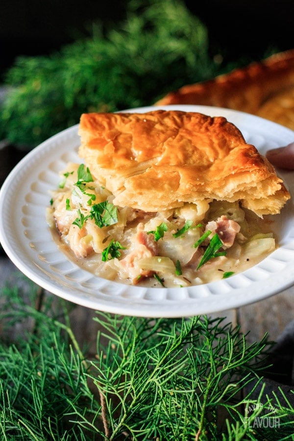 holding a slice of ham and cabbage pie on a plate