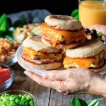 holding a plate of breakfast sandwiches