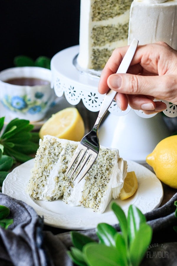 person holding a fork above lemon poppy seed cake