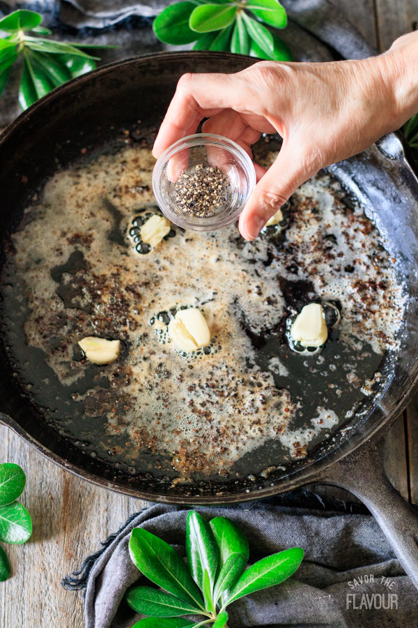 adding black pepper to pan