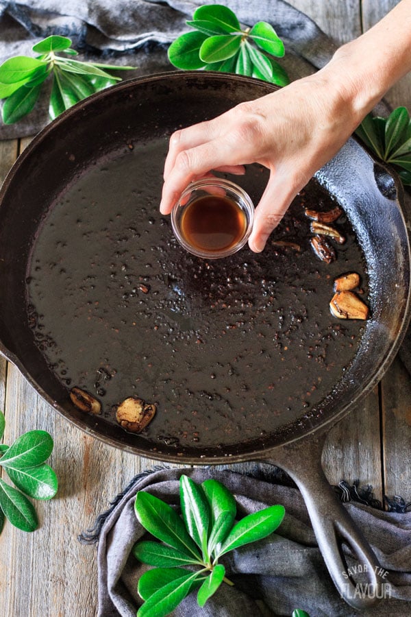 adding Worcestershire sauce to a cast iron skillet