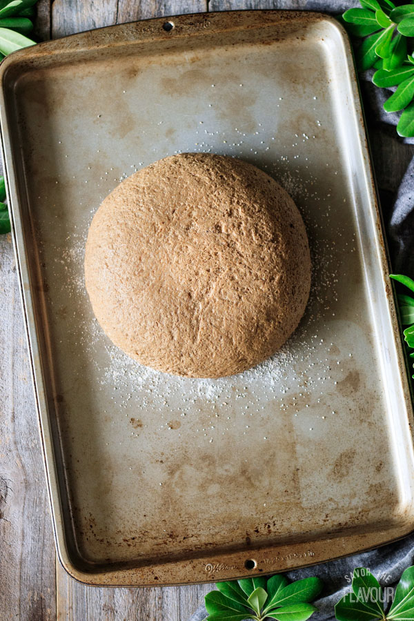 risen loaf of pumpernickel bread on a cookie sheet