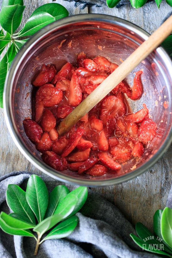 muddling macerated strawberries in a bowl