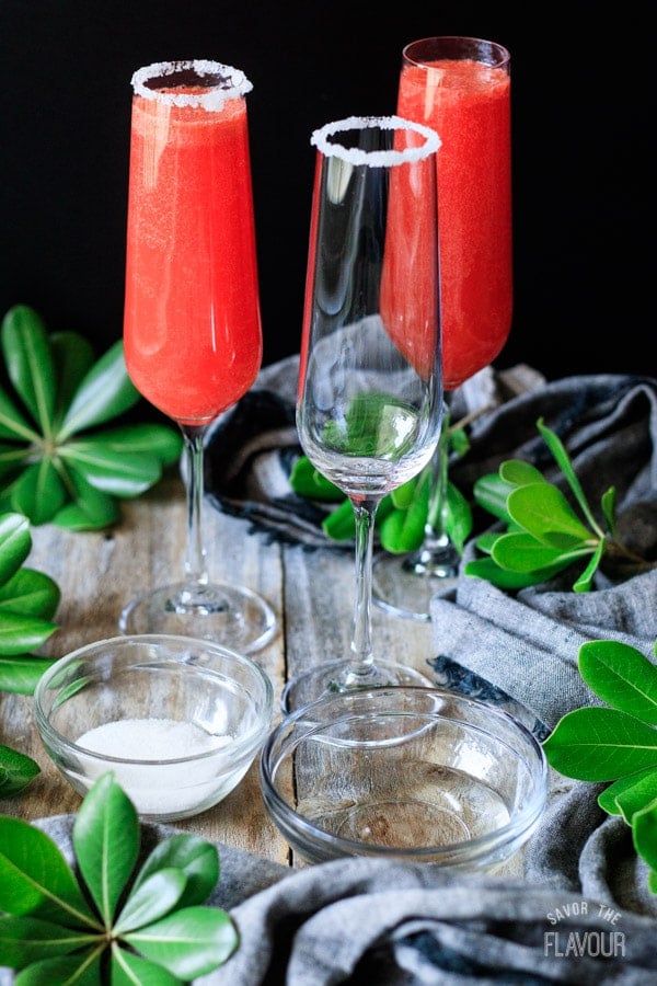 three champagne flutes with sugar and simple syrup