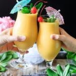 people doing a toast with two glasses of frozen mango daiquiri
