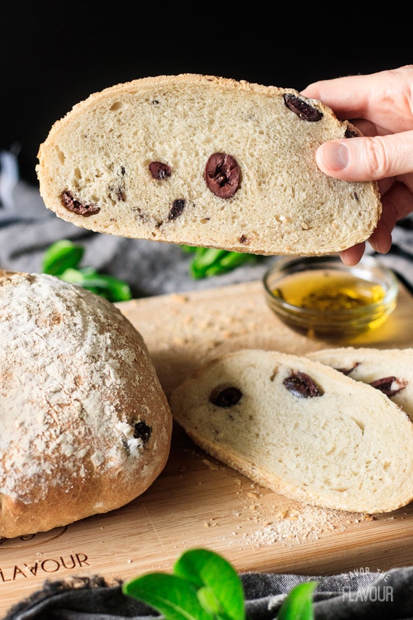person holding a slice of olive bread