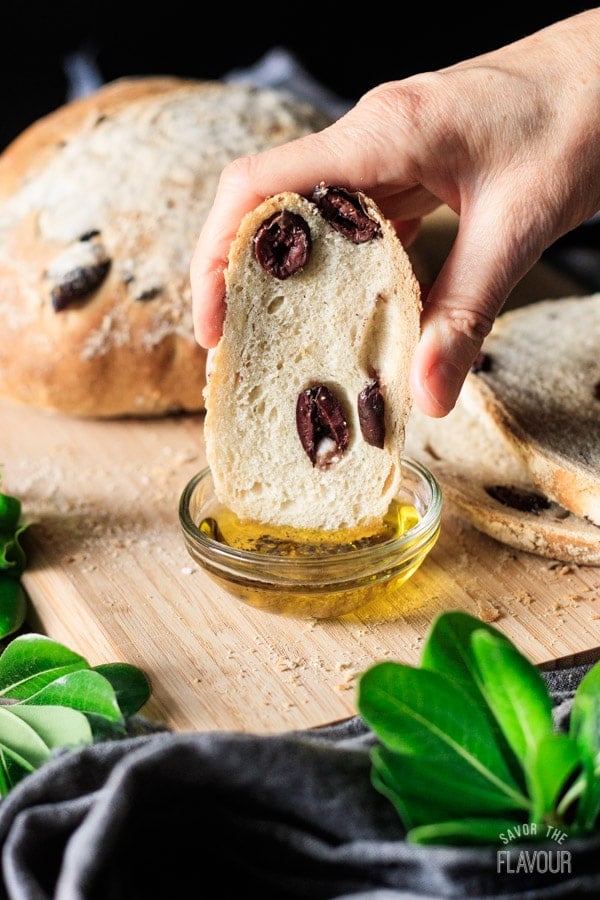 person dipping a slice of olive bread into olive oil