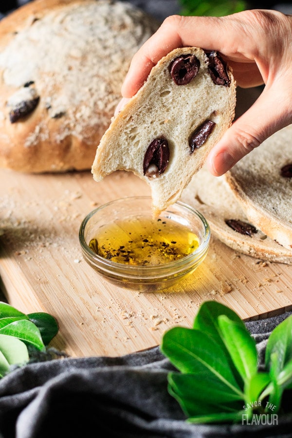 person holding a slice of olive bread