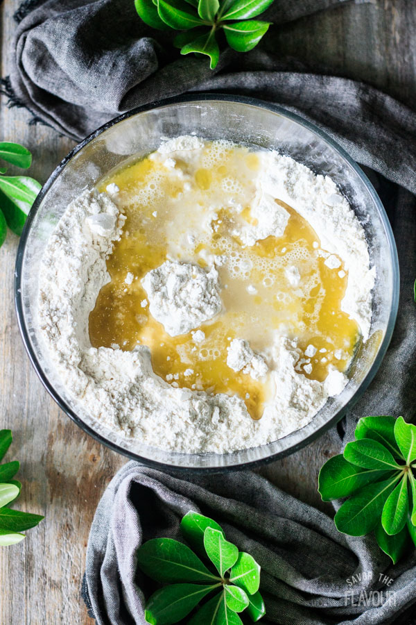 adding olive oil and water to bowl of flour