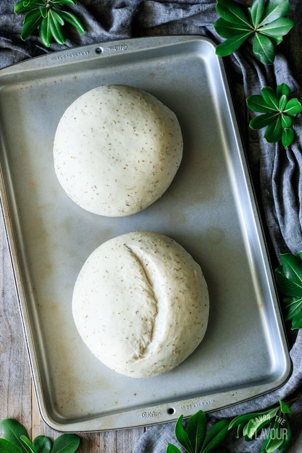two risen loaves of rosemary bread on a cookie sheet