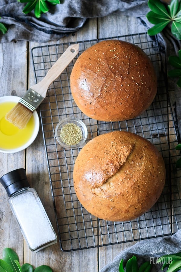 two loaves of rosemary bread with rosemary, salt, and a dish of oil