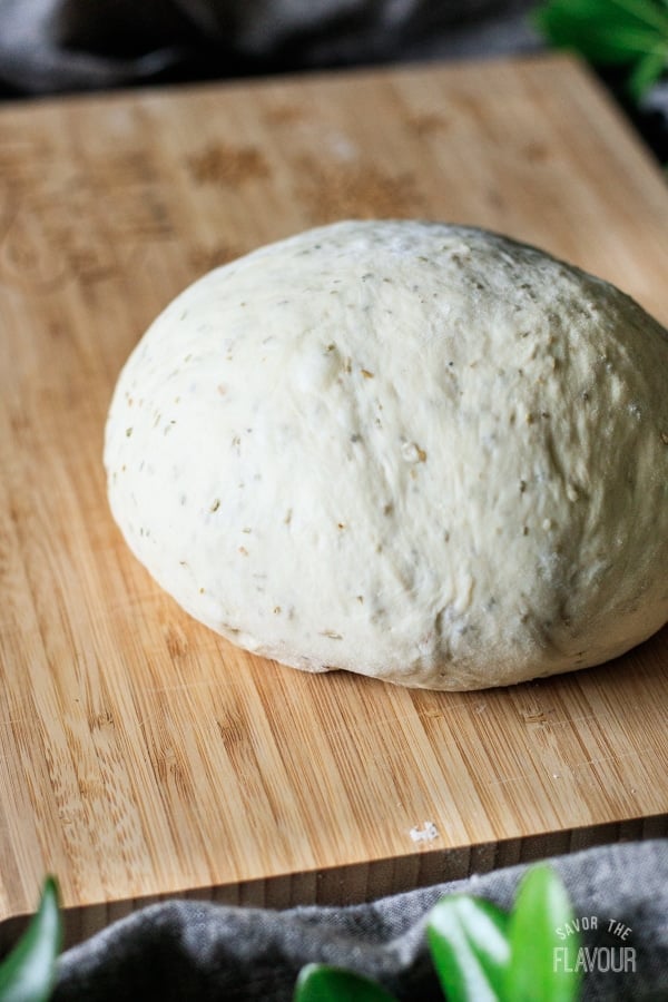ball of rosemary bread dough on a cutting board