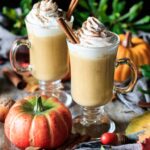 two glasses of pumpkin spice latte with a pumpkin
