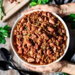 person holding a bowl of lentil stew with kielbasa sausage