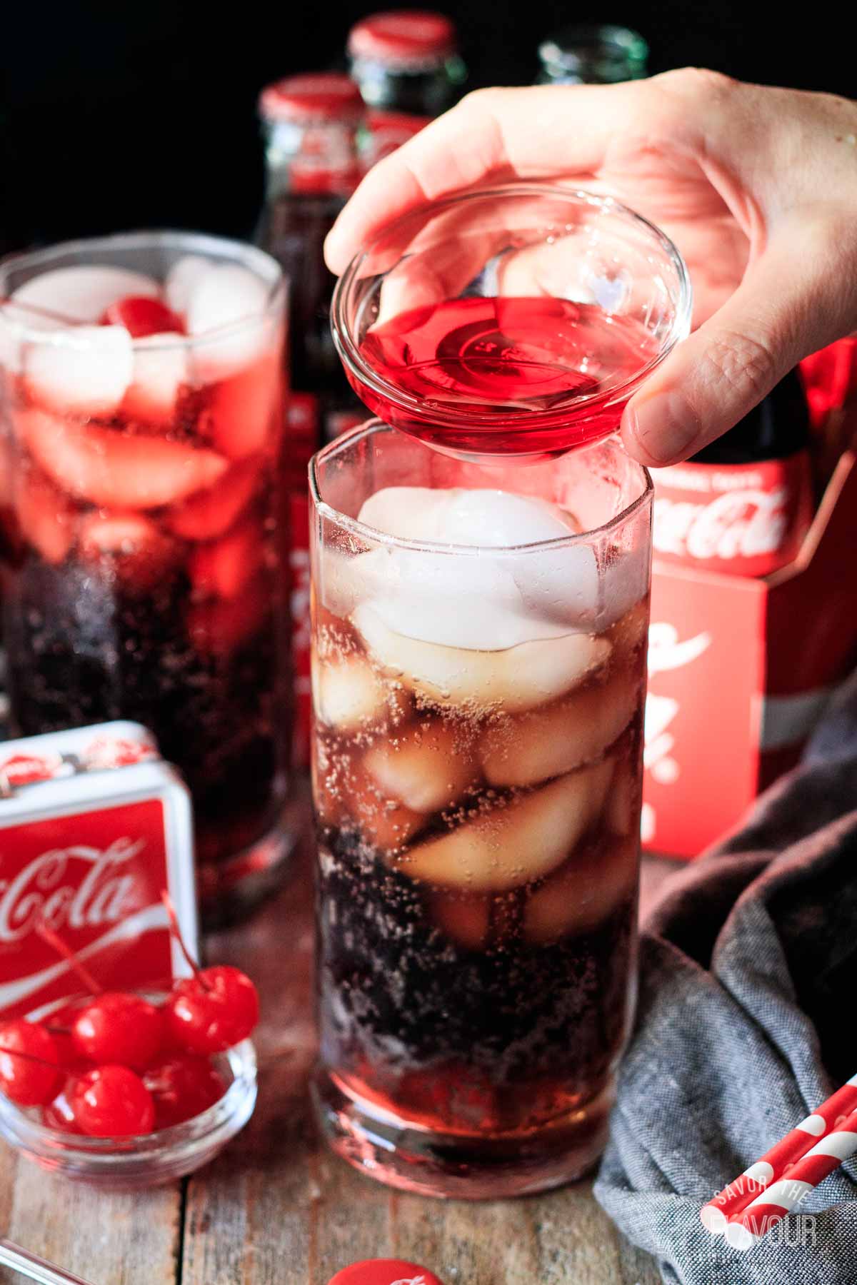 person pouring grenadine into a glass of Coke