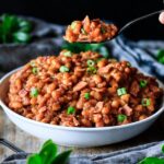 person holding a spoonful of baked beans