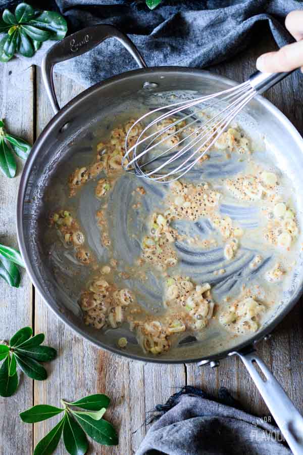 person whisking roux with veggies