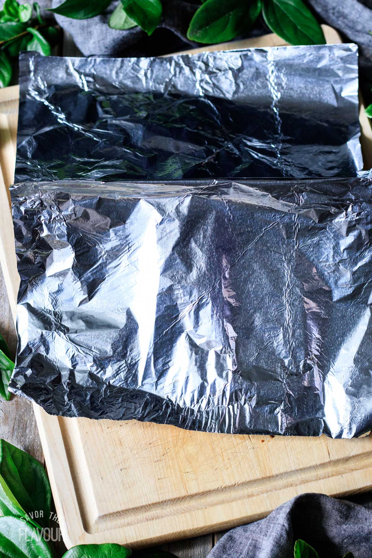 cooked steaks resting on a cutting board and tented with foil