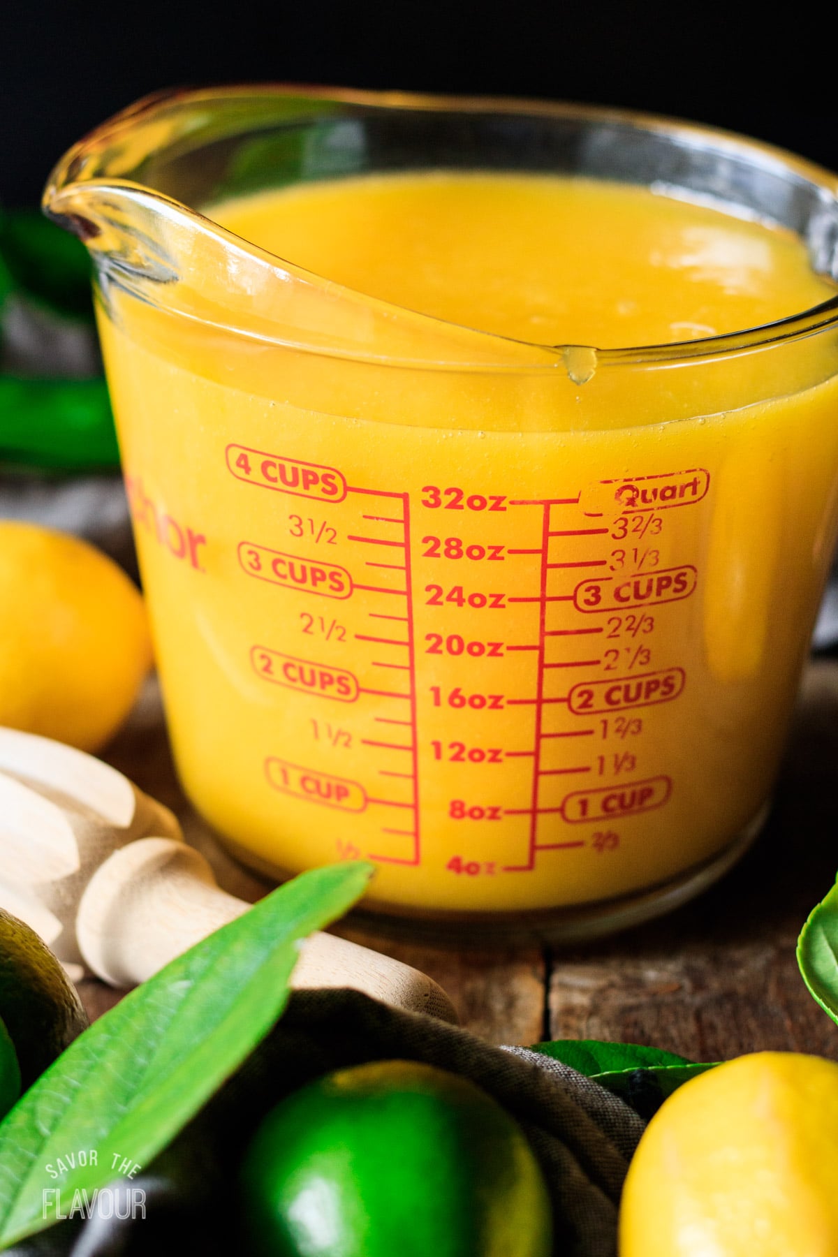 measuring mango lemonade in a glass measuring cup