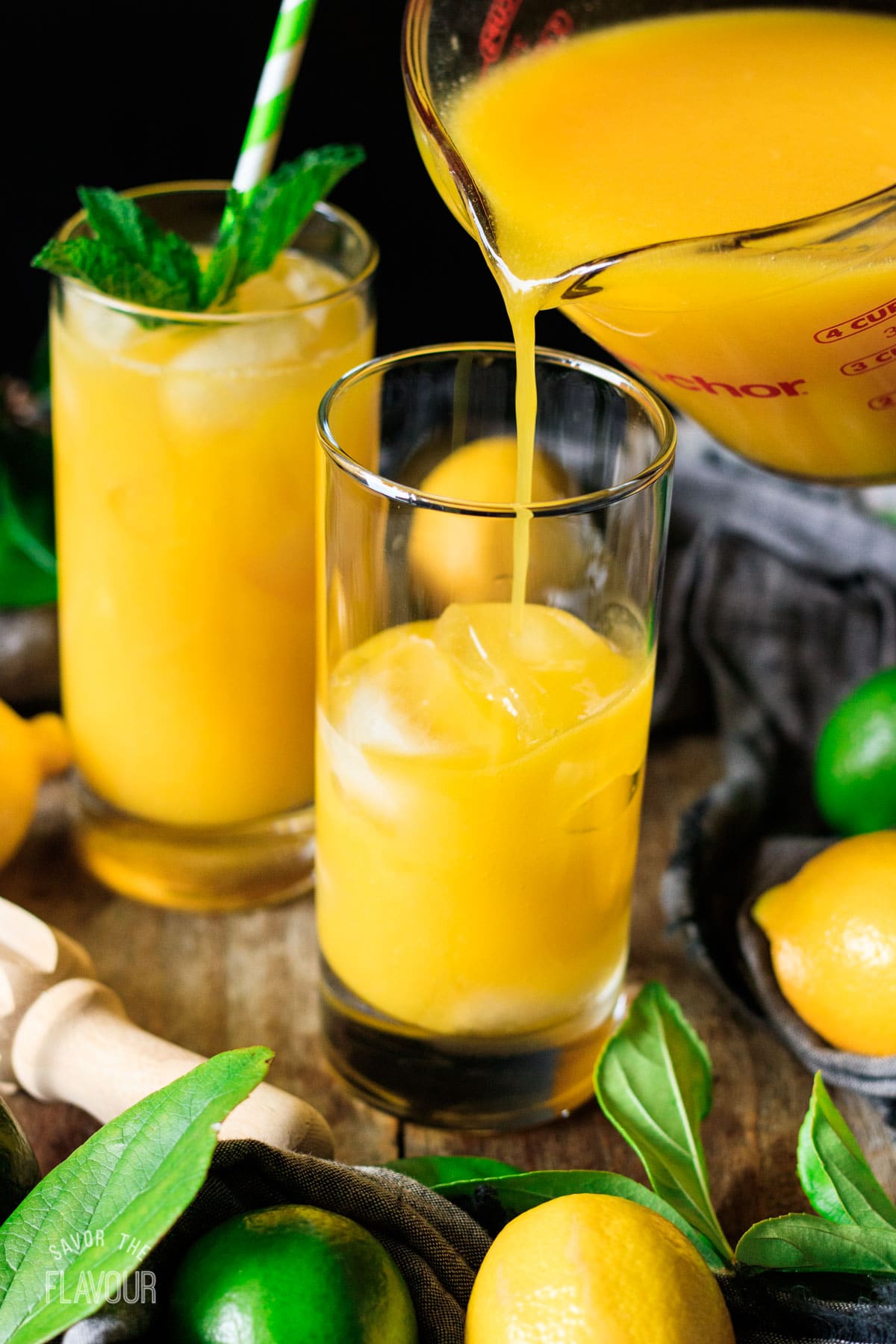 pouring mango lemonade into a glass of ice