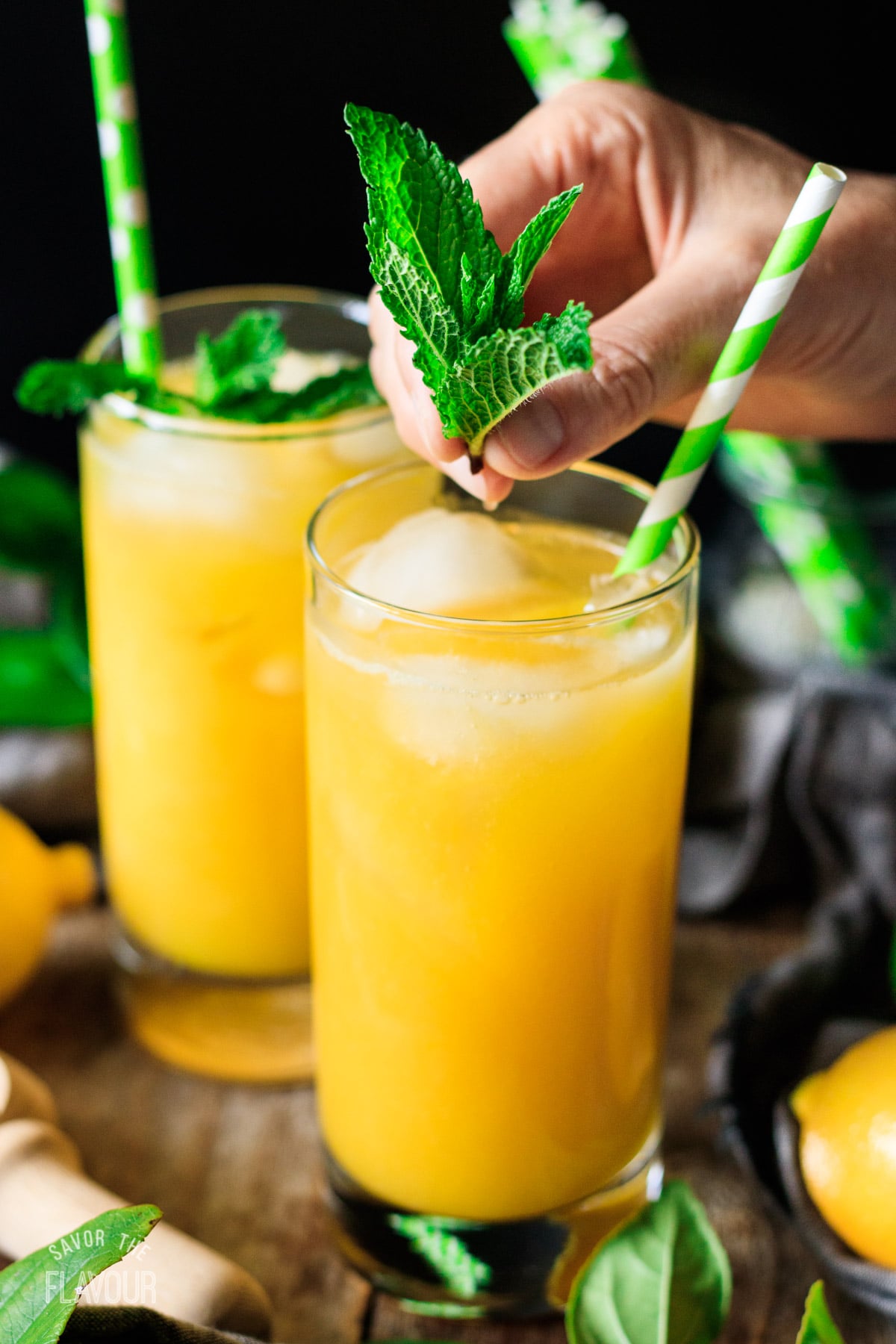 garnishing mango lemonade with a sprig of mint