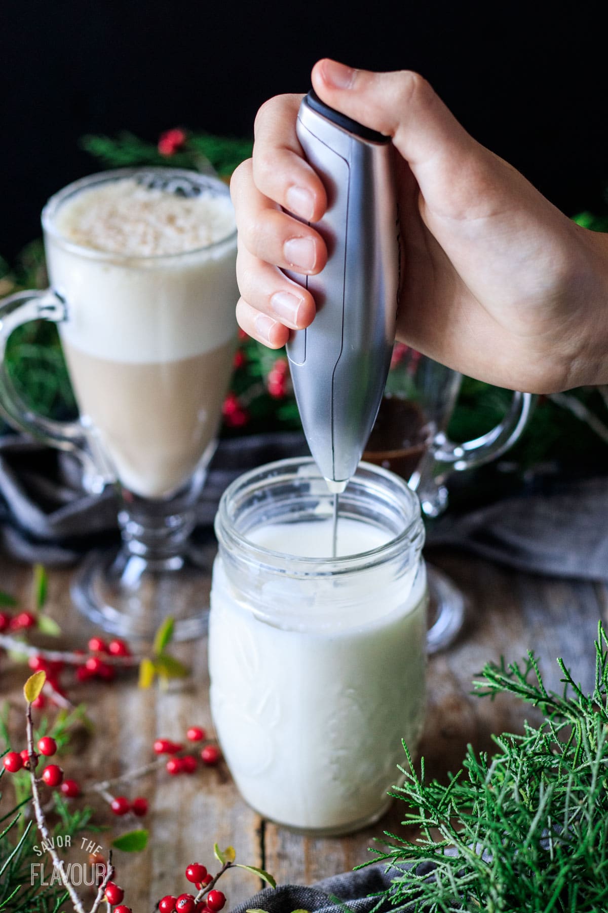 person frothing milk in a mason jar with a milk frother