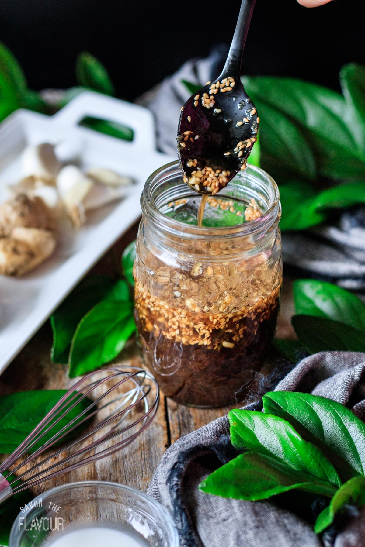 person pouring a spoonful of vegan stir fry sauce into a jar