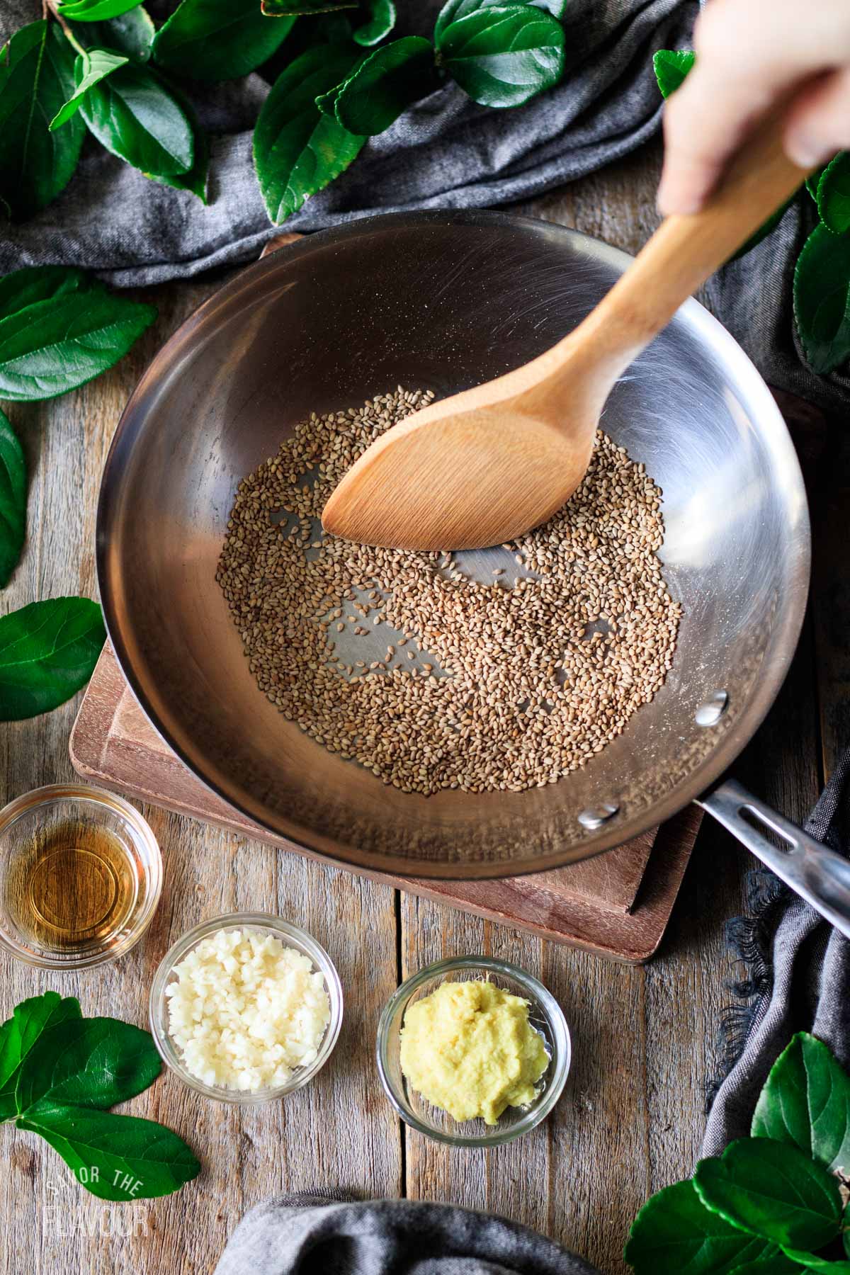 person stirring sesame seeds in a skillet