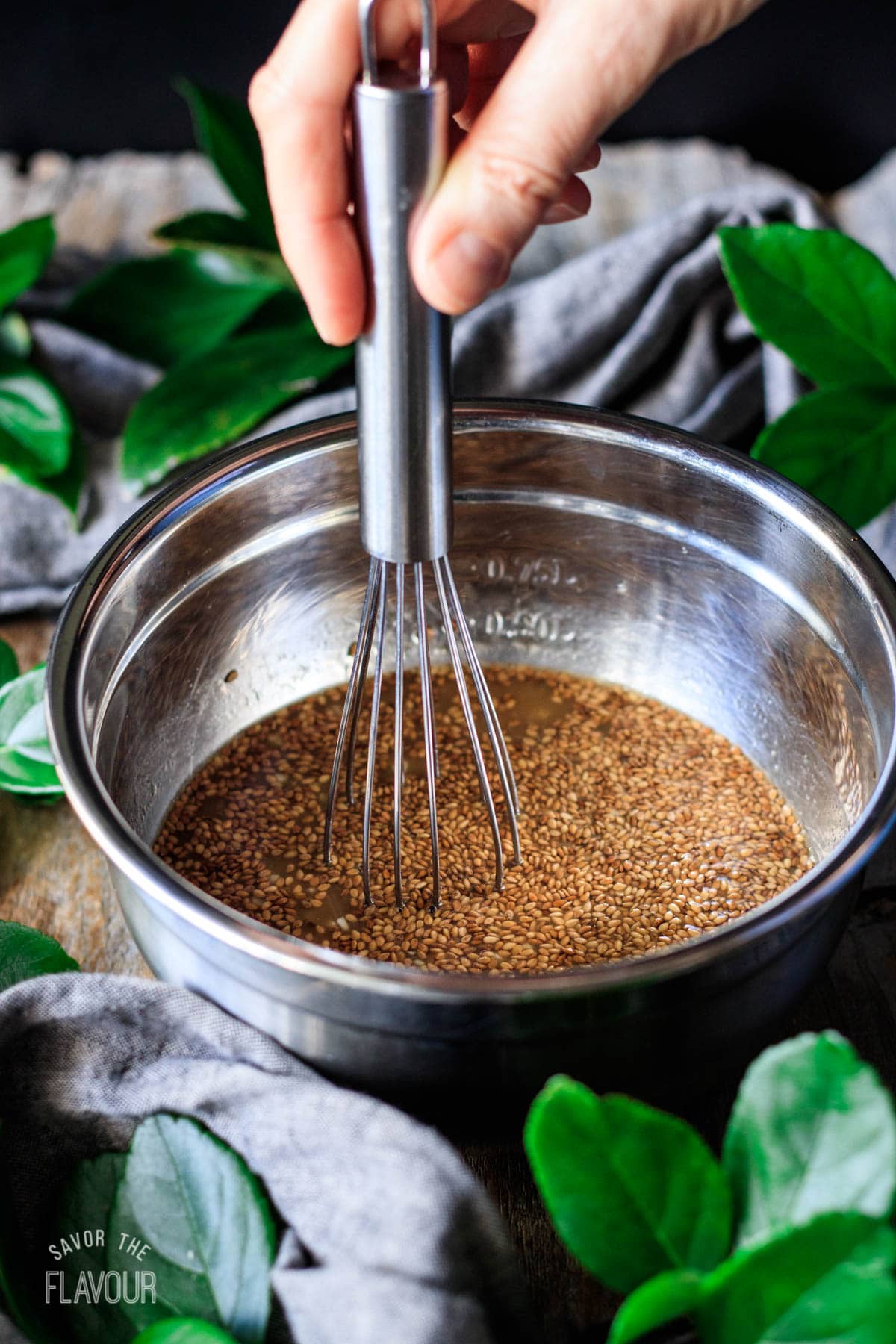 person whisking vegan stir fry sauce in a mixing bowl