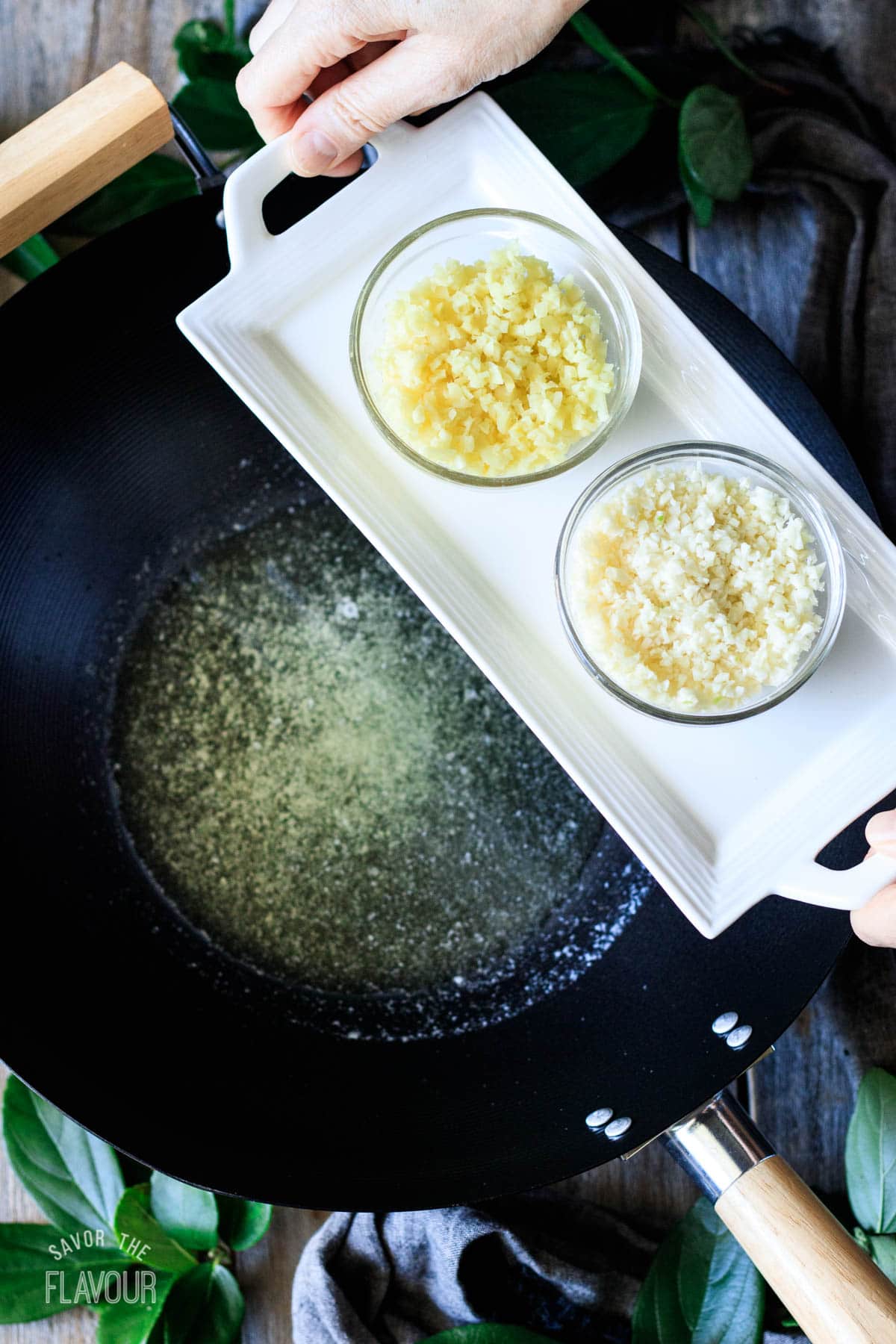 person holding a tray with bowls of minced garlic and ginger
