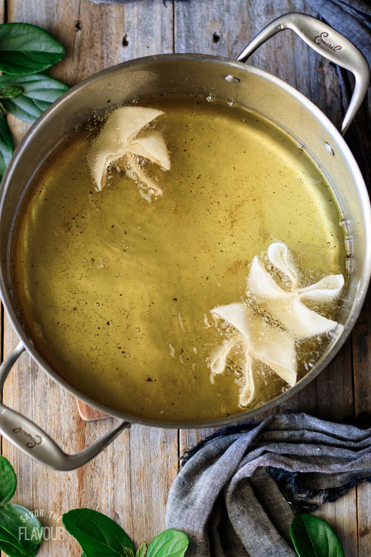 three cream cheese rangoons deep frying in a pot of oil