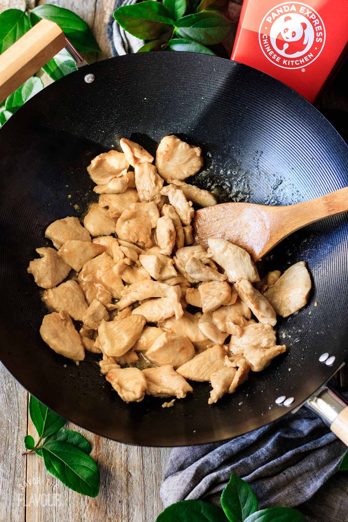person stirring cooked chicken cubes in a wok