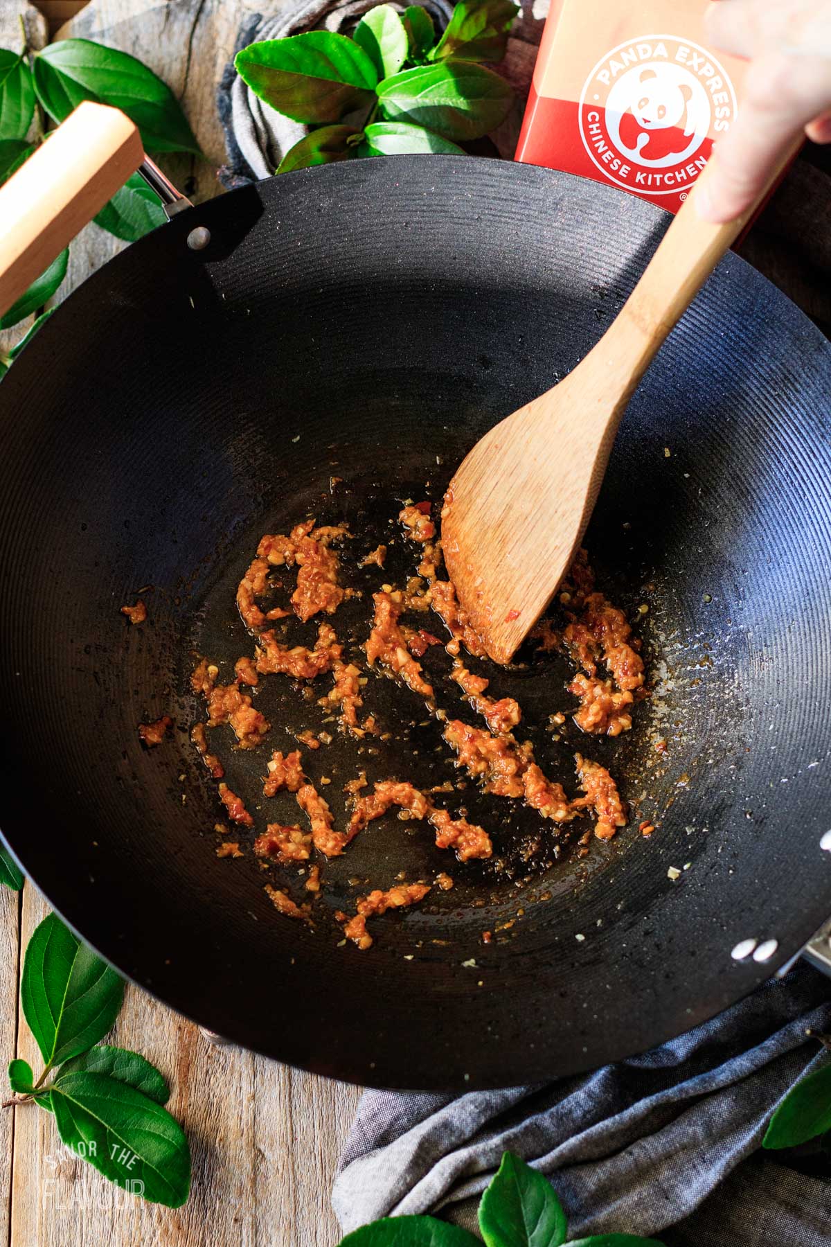 person cooking garlic, ginger, and sambal oelek in a wok