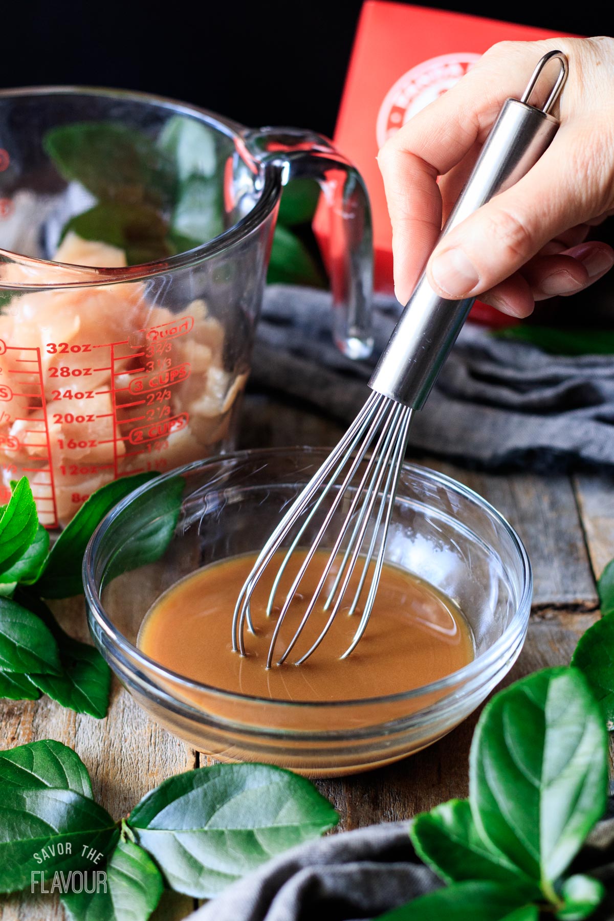 person whisking the chicken marinade in a glass bowl